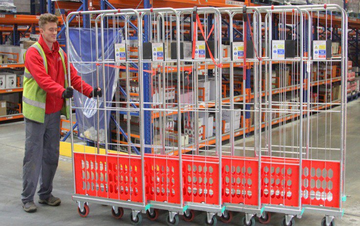 A distribution centre worker pushing multiple trolleys easily due to high quality castors.